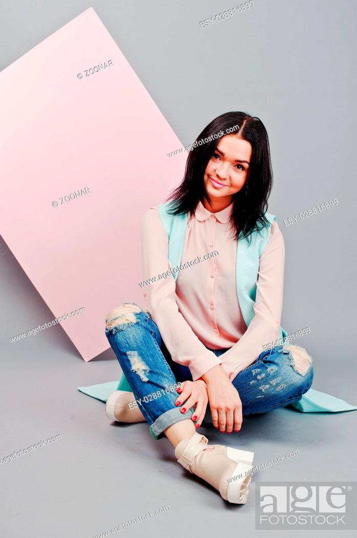 Stock Photo: Full length studio portrait of young girl model at ripped jeans and rose blouse with pink banner board.