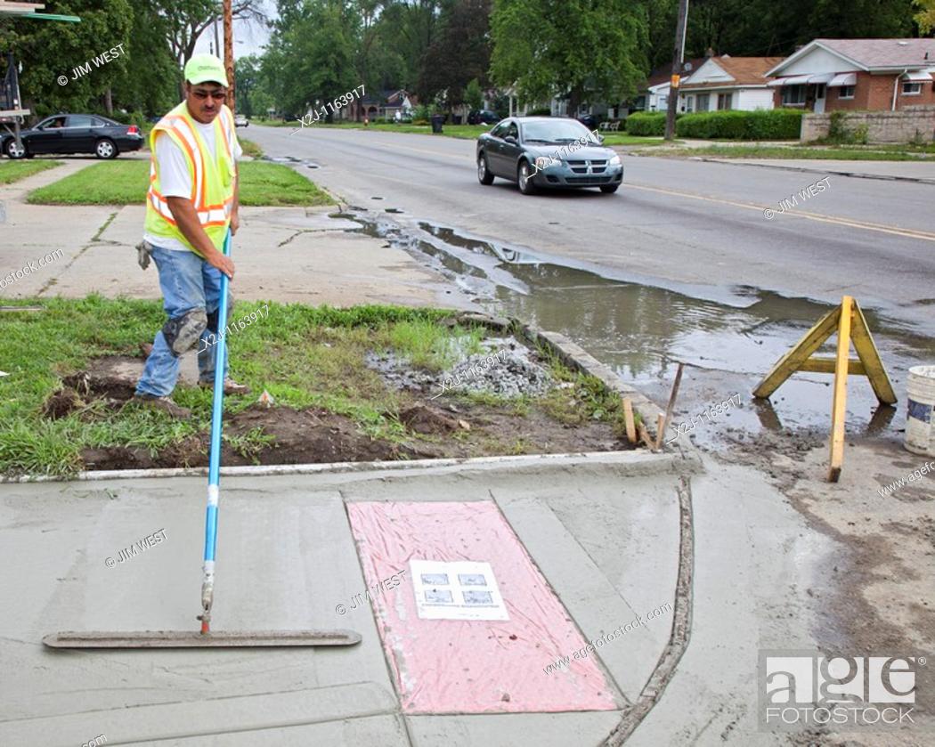Stock Photo: Detroit, Michigan - Workers install a curb ramp at a street intersection to allow access for people with disabilities  The ramps are required by the Americans.