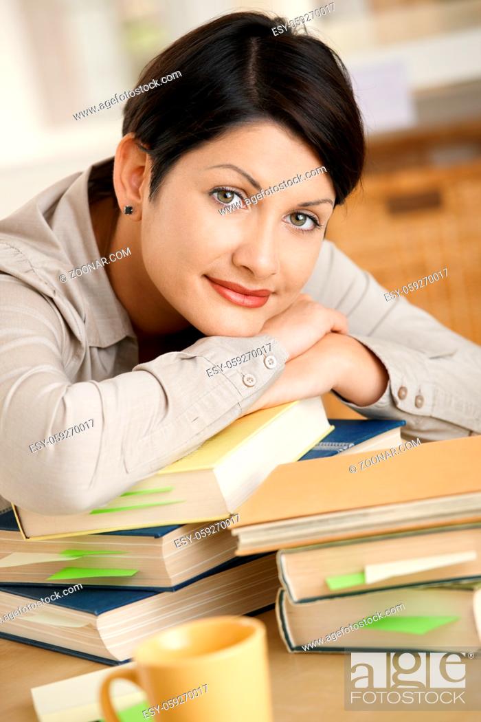 Stock Photo: Tired young woman learning at home, resting on pile of books.