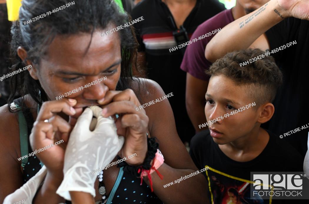 Stock Photo: 25 April 2023, Mexico, Huixtla: A child watches as Deborah Sofia from Venezuela has her mouth sewn shut in a protest. Migrants did so to protest Mexico's.