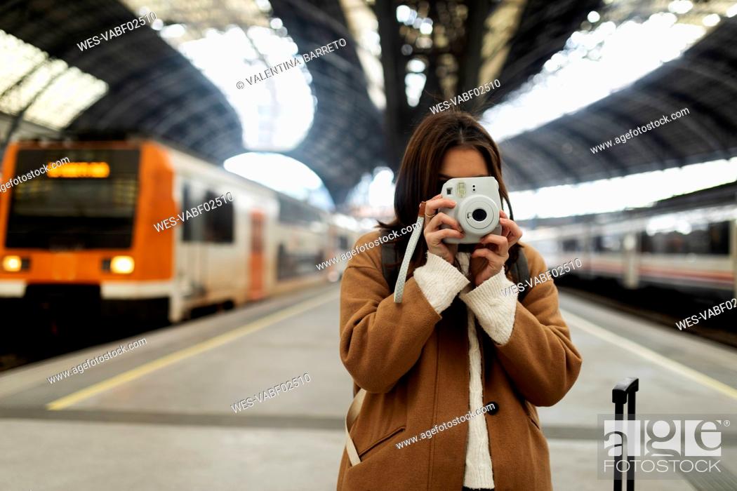 Stock Photo: Young woman taking picture with camera at the train station.