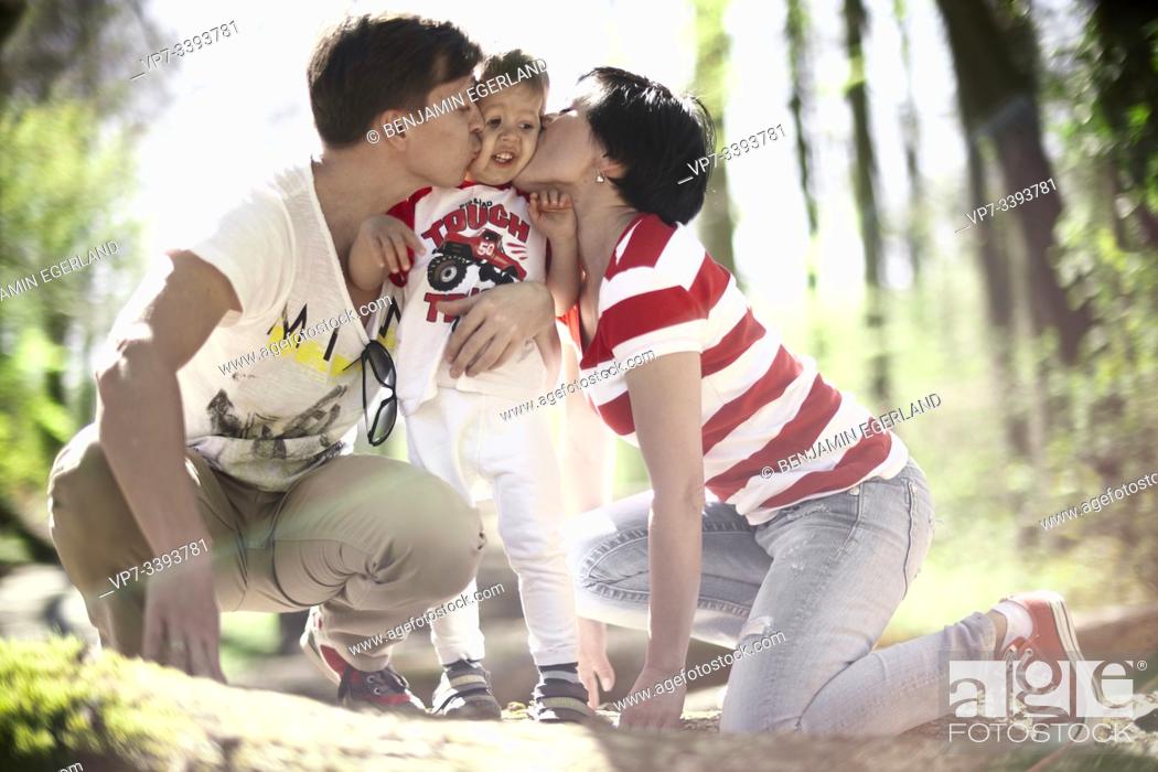 Stock Photo: parents kissing toddler child in forest, at Herrenchiemsee, Chiemsee, Bavaria, Germany.