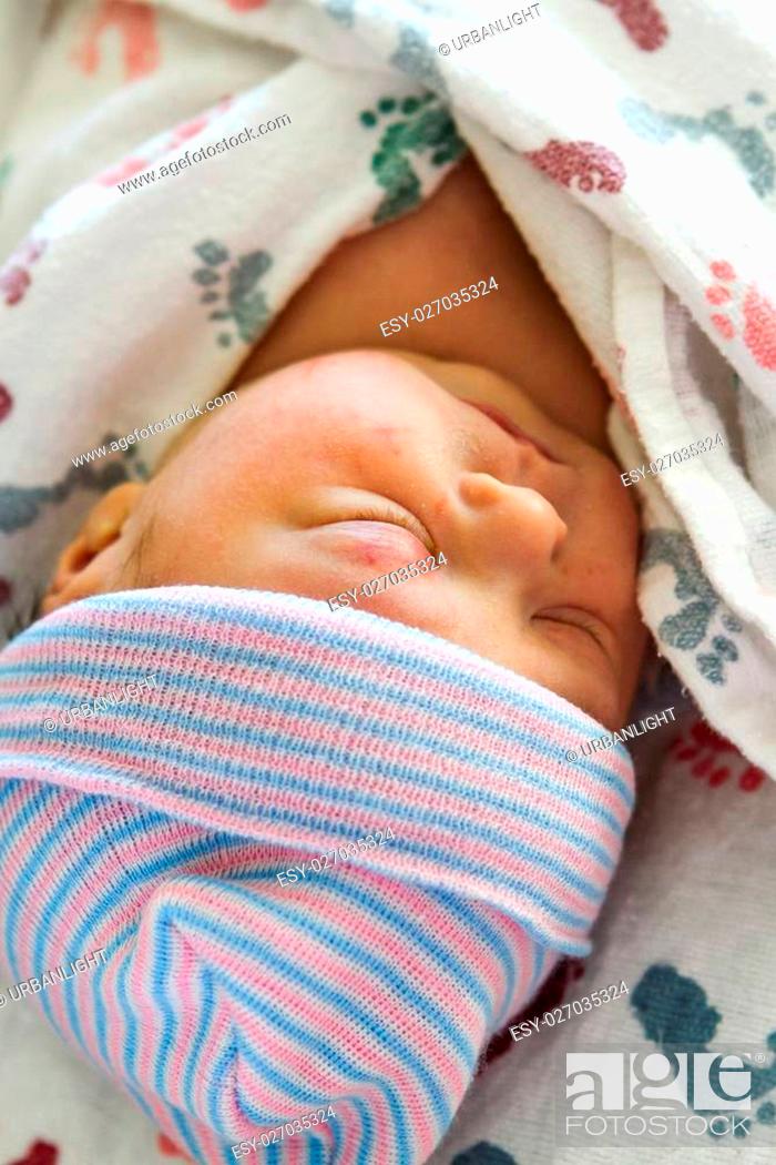 Stock Photo: A newborn baby girl wrapped in a swaddle blanket.