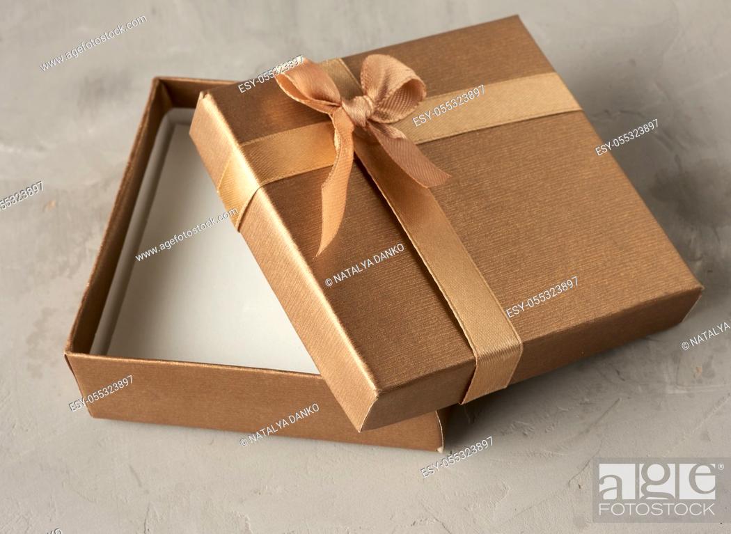 Imagen: open golden square gift box on gray background, top view.