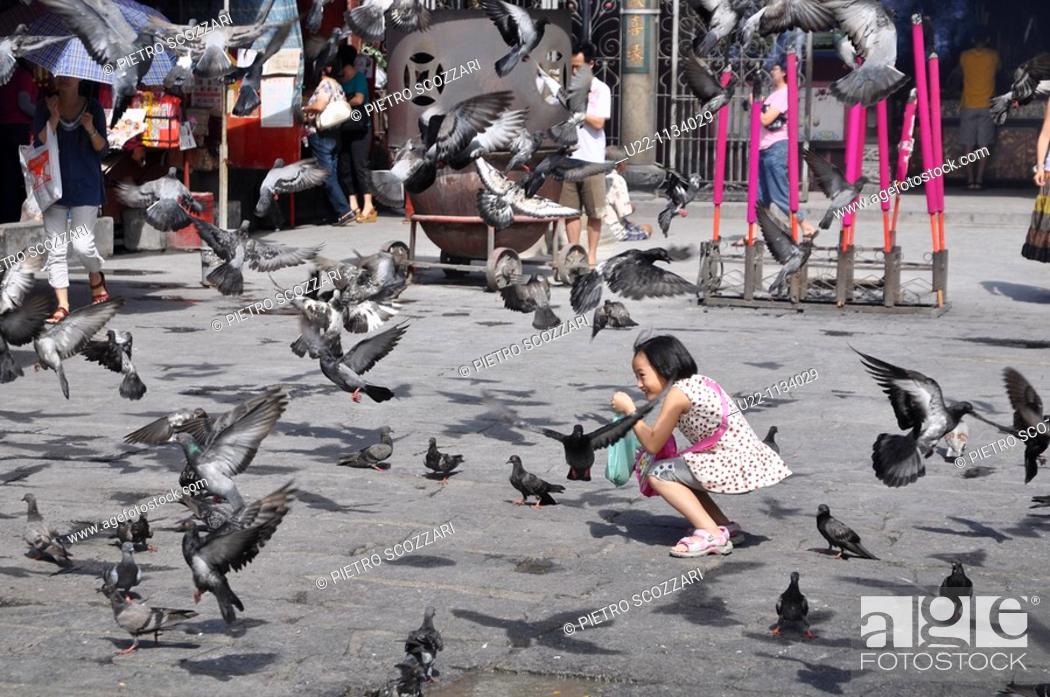 Stock Photo: George Town, Penang (Malaysia): a young girl playing with pigeons in front of the Goddess of Mercy Chinese Temple.