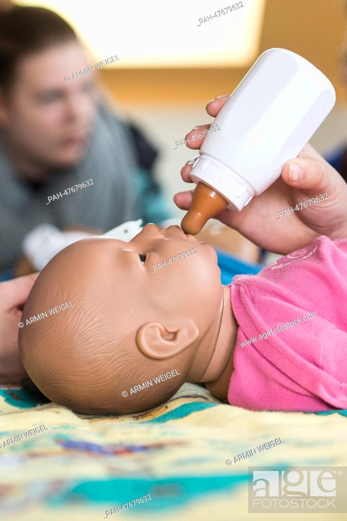 Stock Photo: Teenage girls look after lifelike baby dolls during an internship for parents to prevent young people to get children in Amberg, Germany, 31 March 2014.