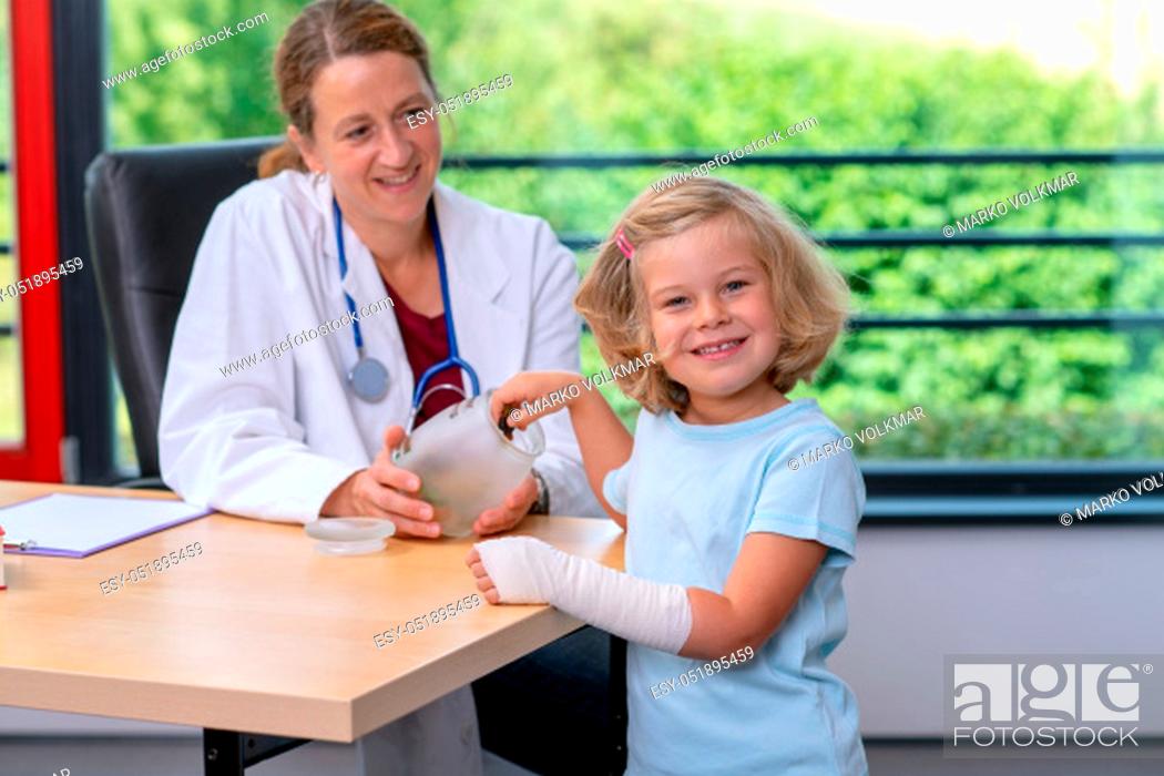 Stock Photo: female pediatrician in white lab coat has candys for a little girl.
