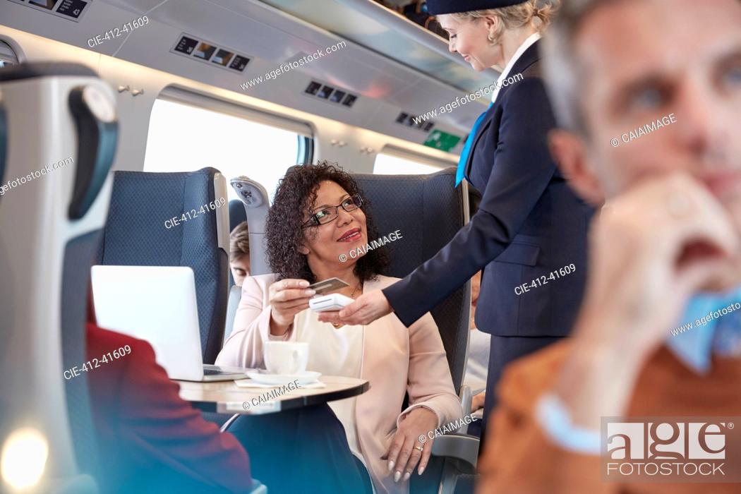 Stock Photo: Woman with credit card using contactless payment, paying attendant on passenger train.