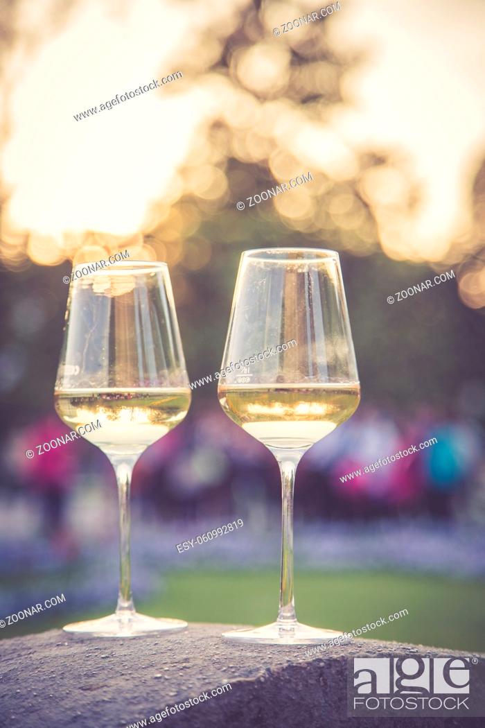 Stock Photo: Glass of white wine on a stone wall in the formal garden. Enjoying it in the own garden in the evening sun.