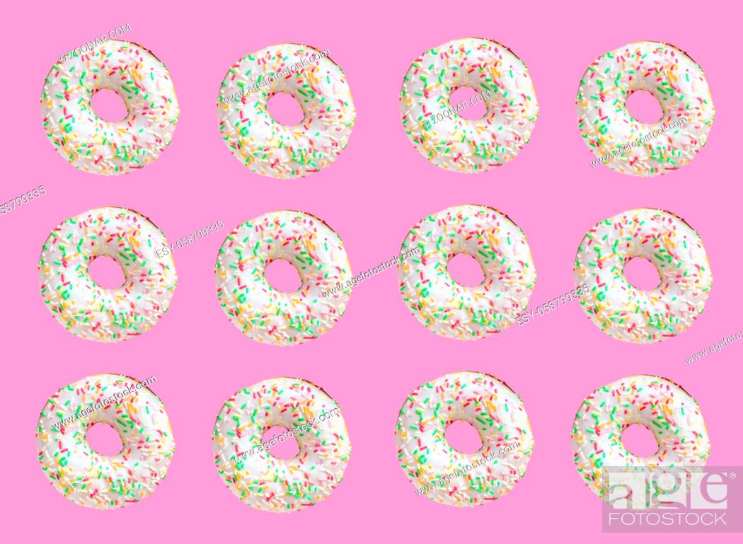 Imagen: Pattern made of ring donuts with white glaze and clourful hundreds and thousands on pink background.