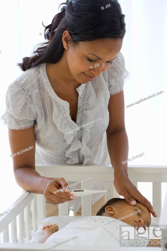 Stock Photo: African American mother checking baby’s temperature.