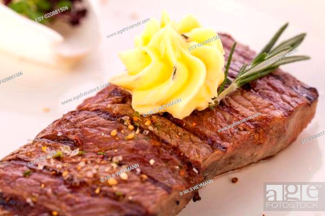 Stock Photo: juicy grilled beef steak with homemade herb butter on a plate isolated against white background.