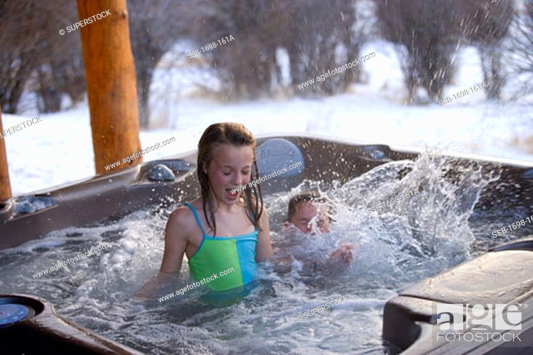 Stock Photo: Girl in a hot tub with her brother splashing water.