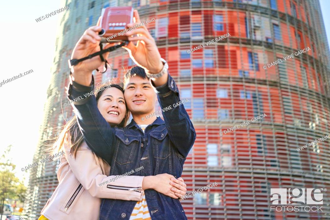 Stock Photo: Portrait of couple talking selfie with instant camera, Barcelona, Spain.