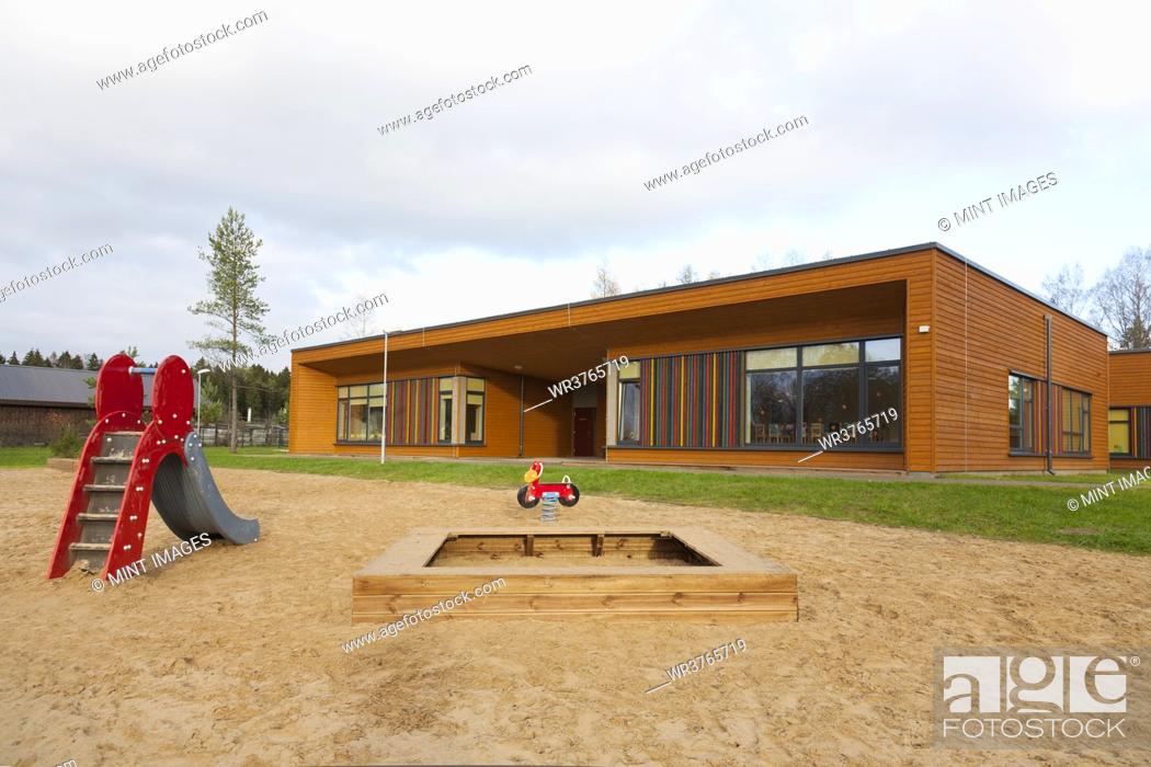 Stock Photo: A modern building, nursery or pre-school, a large sand pit play area with a slide.