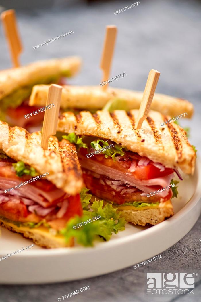 Stock Photo: Appetizing fresh and healthy grilled club sandwiches with ham, cheese, tomato and vegetables served on a plate. Fast food concept.