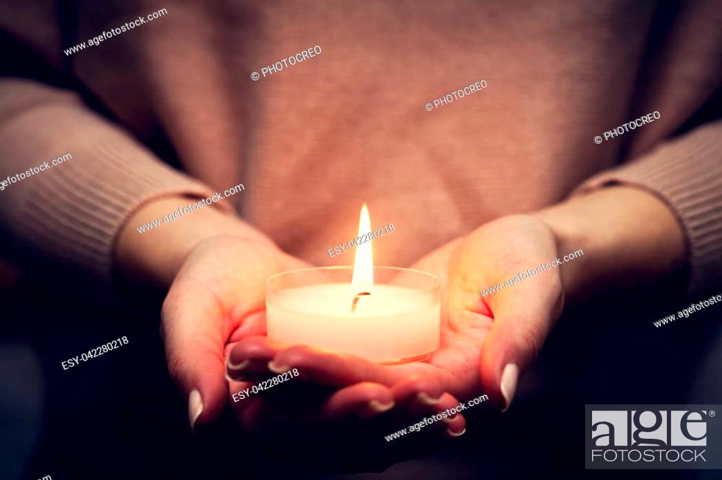 Stock Photo: Candle light glowing in woman's hands. Praying, faith, religion concept.