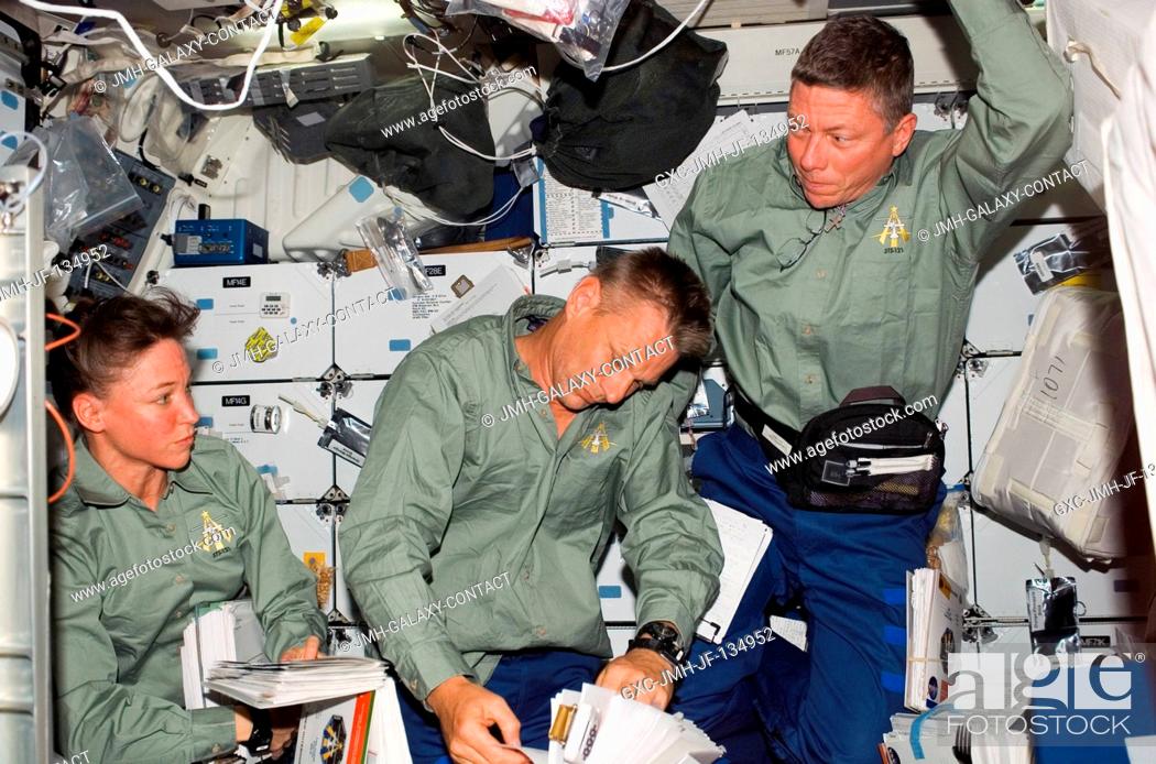 Stock Photo: Astronauts Lisa M. Nowak (left), Piers J. Sellers and Michael E. Fossum, all STS-121 mission specialists, look over procedures checklists on the middeck of the.