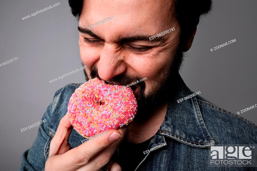 Stock Photo: Hungry overweight man eating donuts isolated on grey background. High quality photo.