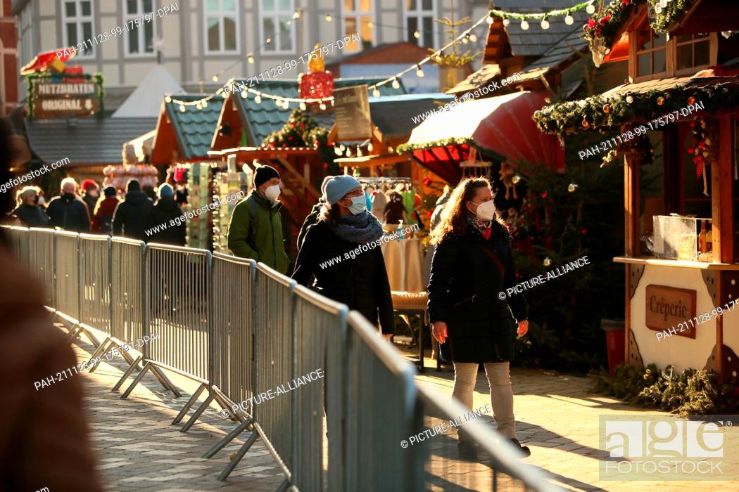 Stock Photo: 28 November 2021, Saxony-Anhalt, Quedlinburg: People visit the fenced Christmas market in the Advent city of Quedlinburg.