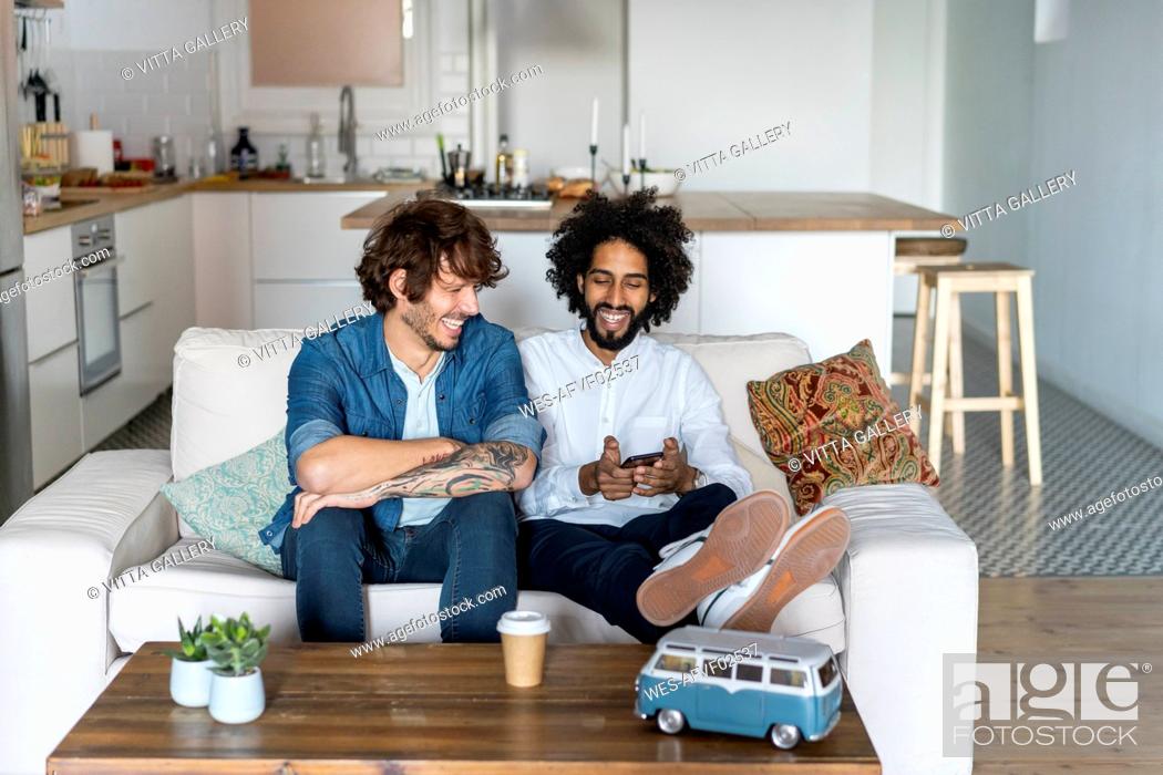 Stock Photo: Friends sitting on couch, planning road trip.