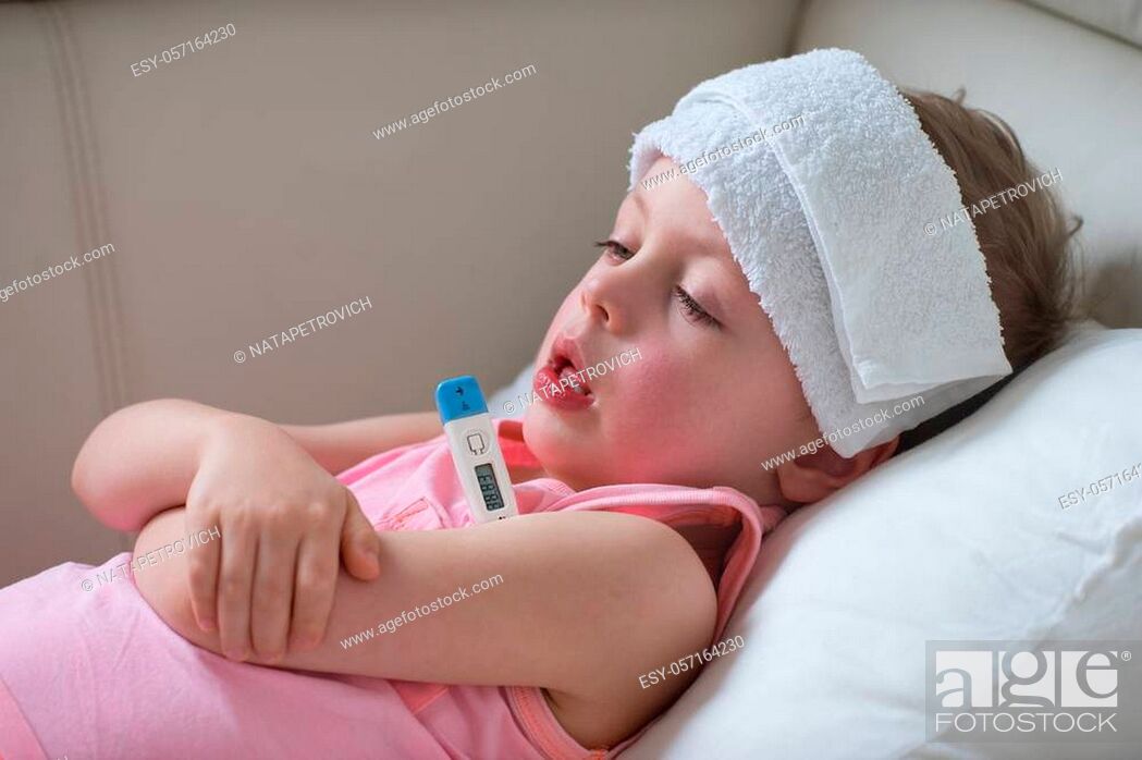 Stock Photo: Sick child with high fever laying in bed and holding thermometer. Compress on forehead.