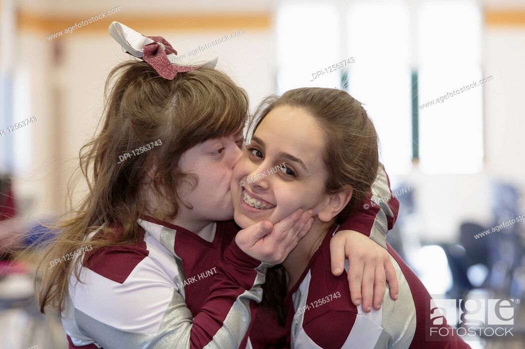 Stock Photo: Cheerleader with Down Syndrome kissing another cheerleader.