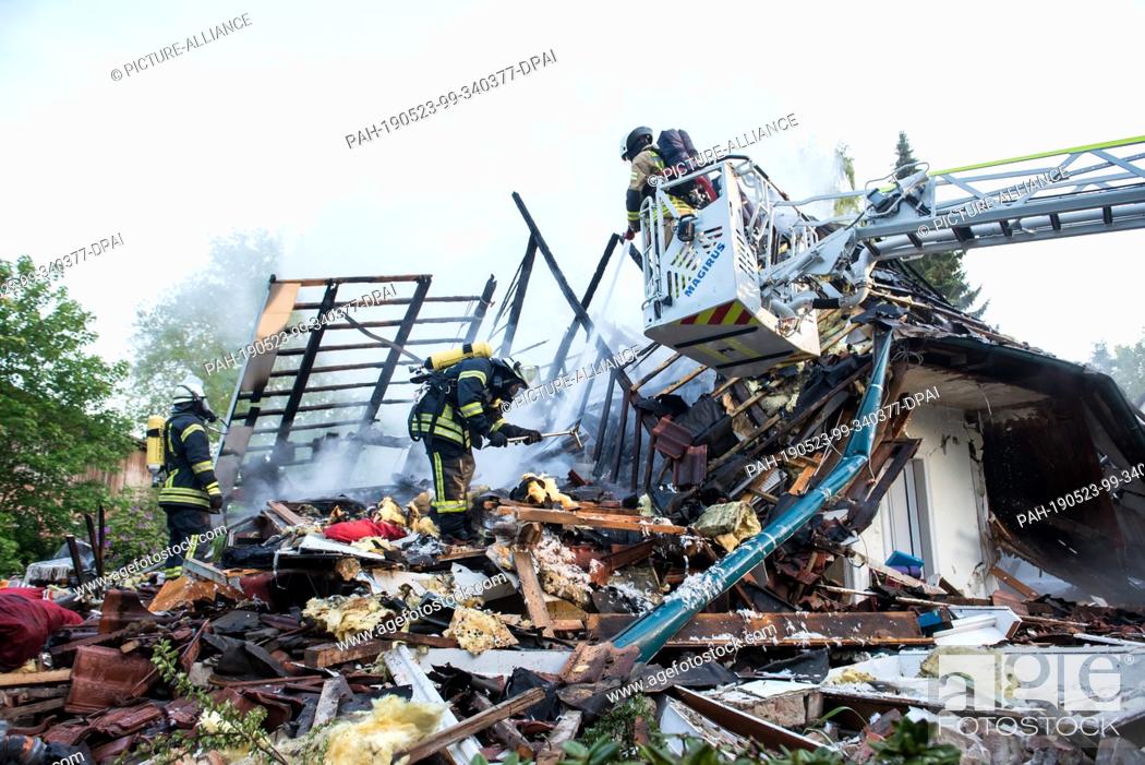 Stock Photo: 23 May 2019, Schleswig-Holstein, Wohltorf: Firefighters are standing in the ruins of a house that was destroyed in a fire.