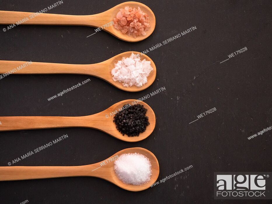 Imagen: Wooden spoons with himalayan salt, black hawaii salt, common salt and salt flakes on a slate plate.