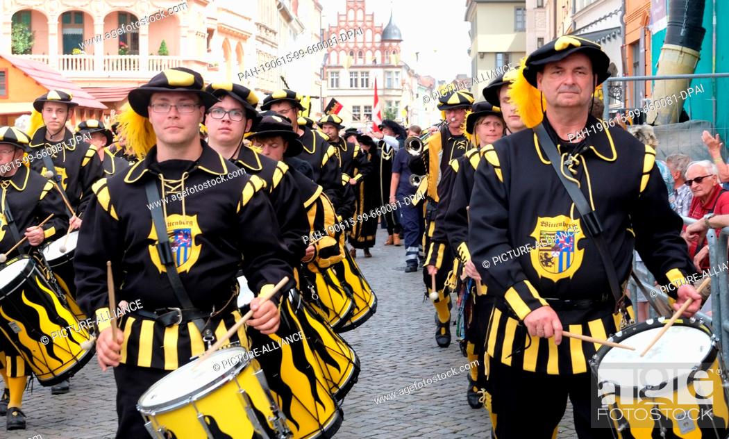 Stock Photo: 15 June 2019, Saxony-Anhalt, Wittenberg: Participants of a parade parade through the city centre with drums. For the three-day city festival ""Luthers Hochzeit.