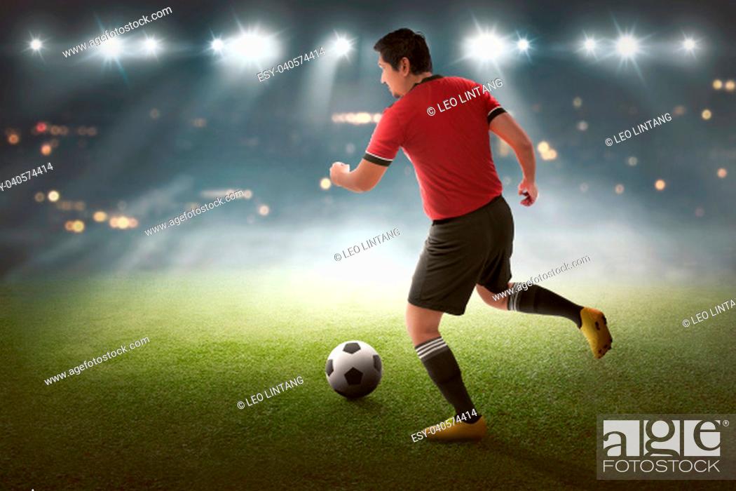 Stock Photo: Young asian soccer player with the ball on the stadium.