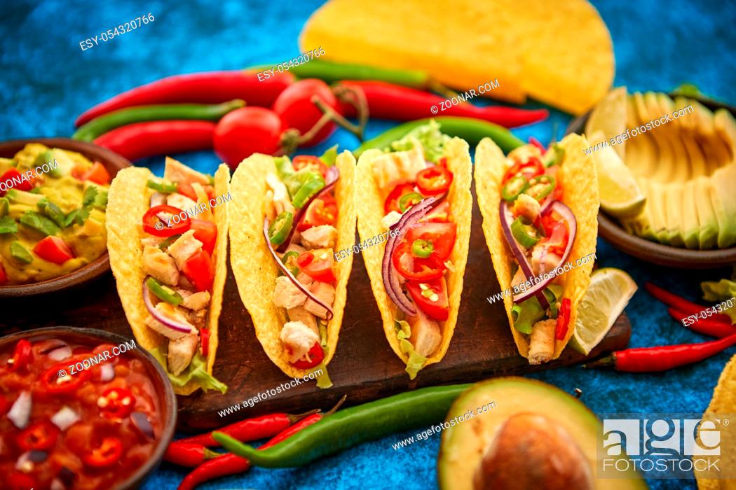Stock Photo: Mexican taco with chicken meat, jalapeno, fresh vegetables served with guacamole and tomato salsa. Latin american food. Placed on blue table.
