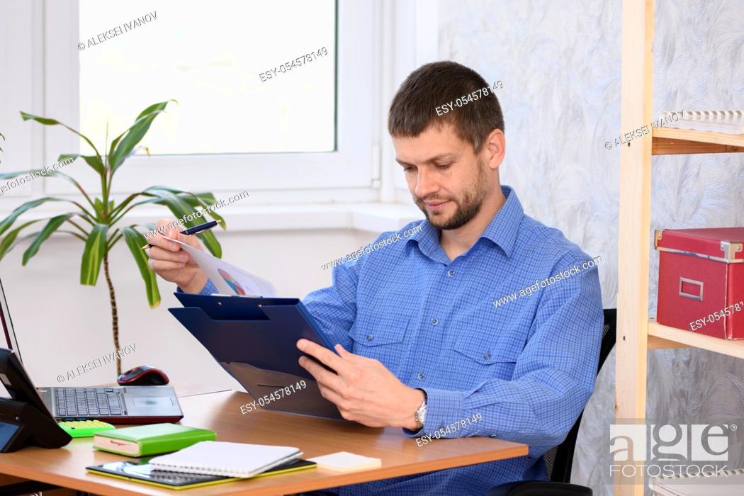 Stock Photo: Business man reads a printed report in a folder.