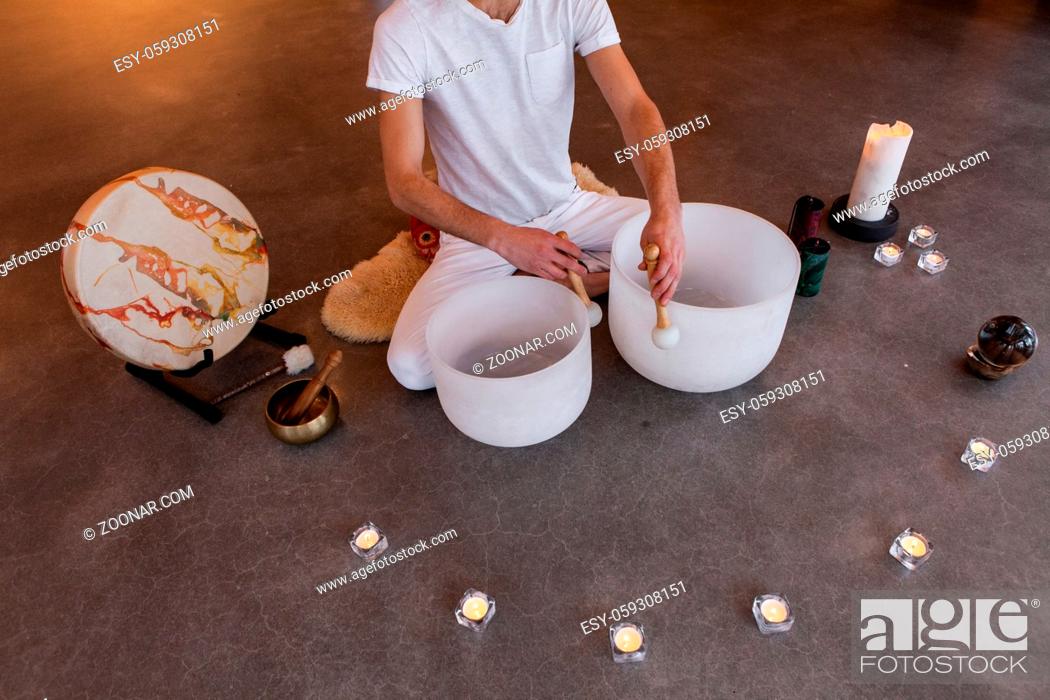 Stock Photo: Man sitting in indian with his two big crystal bowls and his native sacred drum, playing sacred music in a meditative state. Shot from above.