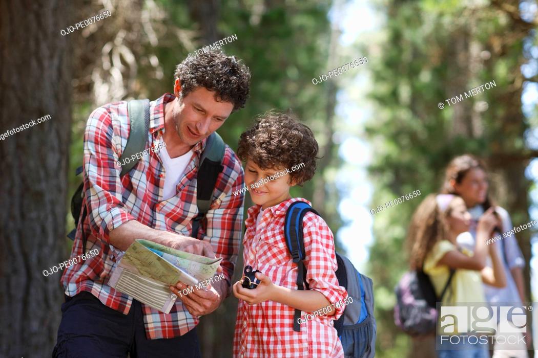 Stock Photo: Father and son looking at map in woods.