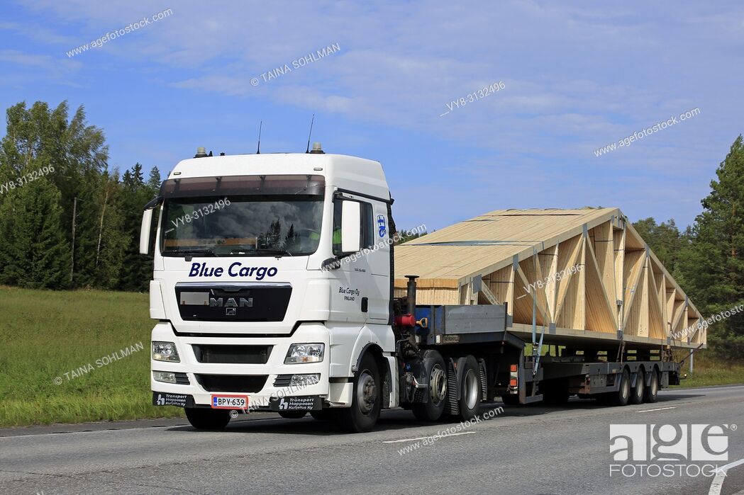 Stock Photo: UURAINEN, FINLAND - AUGUST 25, 2018: White MAN TGX 26. 480 semi truck of Blue Cargo Oy transports roof truss on flat trailer along highway.