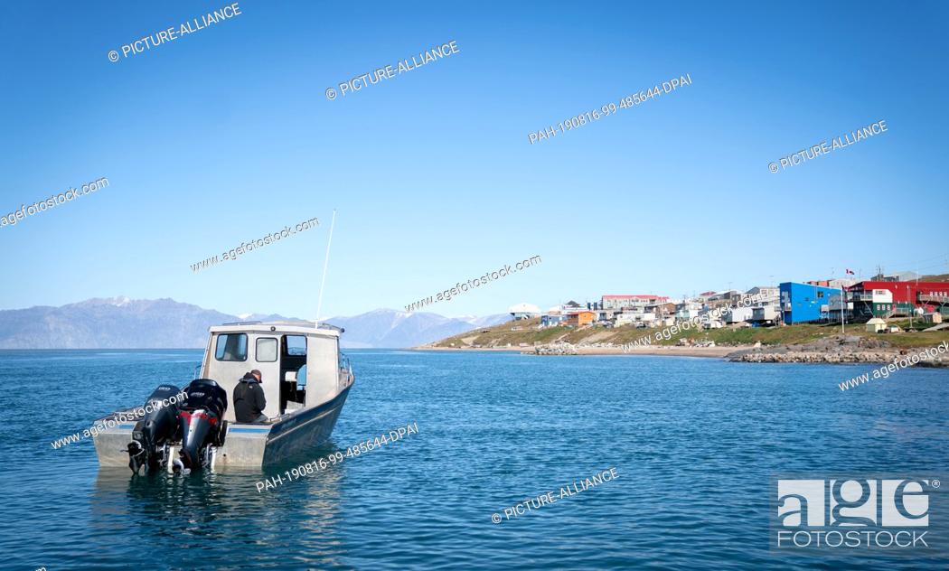 Stock Photo: 15 August 2019, Canada, Pond Inlet: A motorboat lies in front of the village Pond Inlet, in the Canadian Arctic, in the sea.
