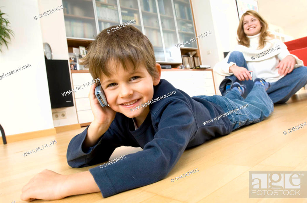 Stock Photo: Portrait of a son using a mobile phone with his mother sitting behind him.