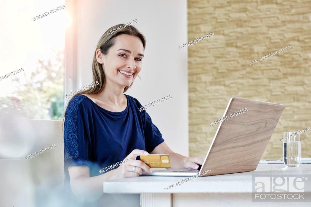 Stock Photo: Portrait of smiling woman at home shopping online.