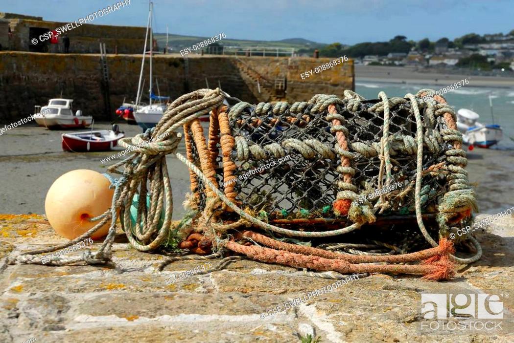 Stock Photo: One empty lobster pot on harbour wall.