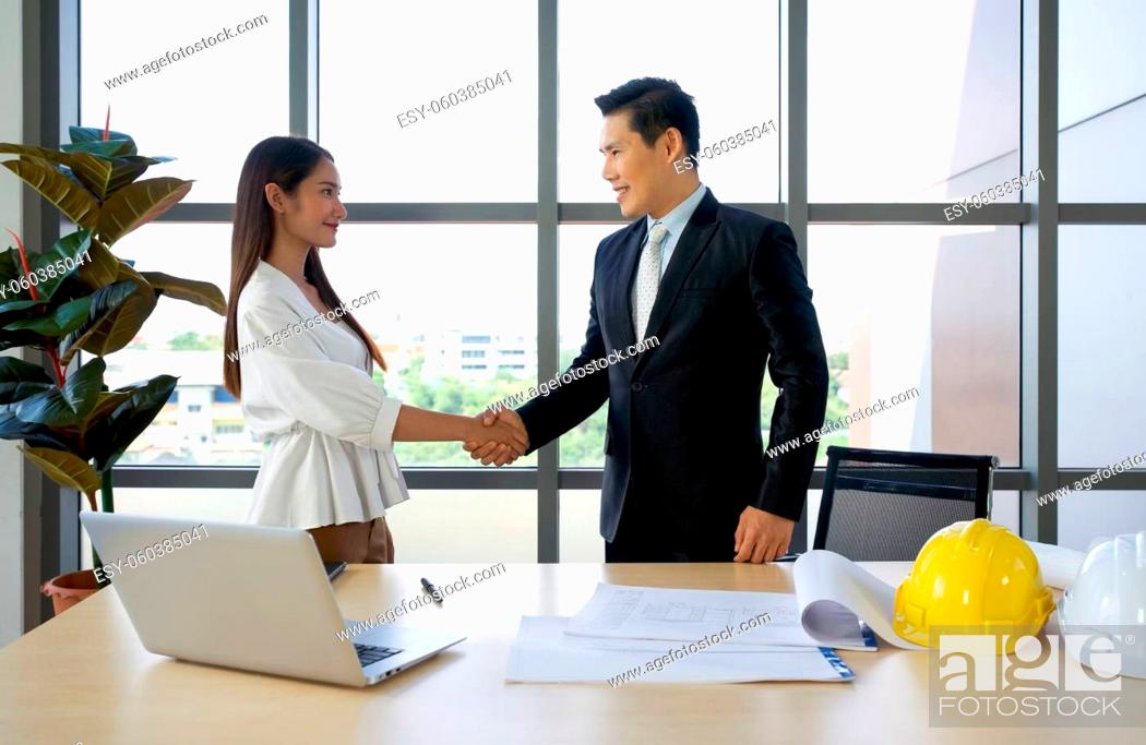 Stock Photo: Asian project owner in suit and his Business partners shaking hands after checking the construction drawing. Morning work atmosphere in a modern office.
