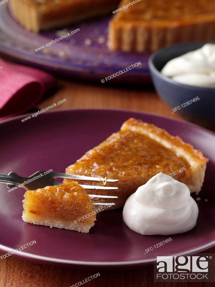 Photo de stock: A slice of treacle tart on a plate with the whole tart behind.