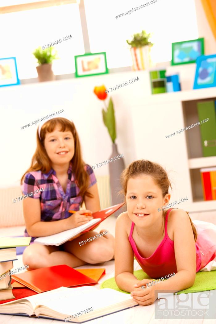 Stock Photo: Portrait of girls doing homework together, smiling at camera.