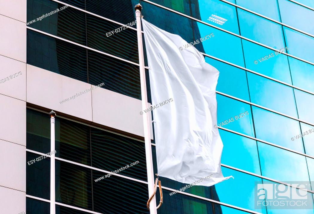 Stock Photo: White flag waving in the wind with office building in the background. Perfect mockup to add any logo, symbol or sign.