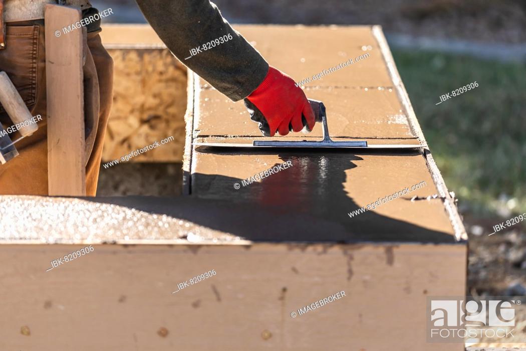 Stock Photo: Construction worker using trowel on wet cement forming coping around new pool.