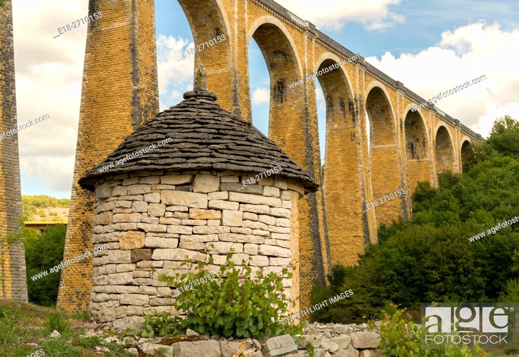 Stock Photo: France, Midi-Pyrénées, Lot, Souillac. High arching, stone supports of railway bridge over deep valley. Old stone shed in the foreground.