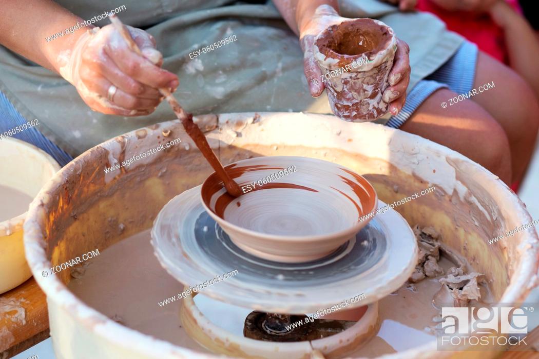 Stock Photo: Hands of girl potter, creating an earthen jar on the circle, close-up.