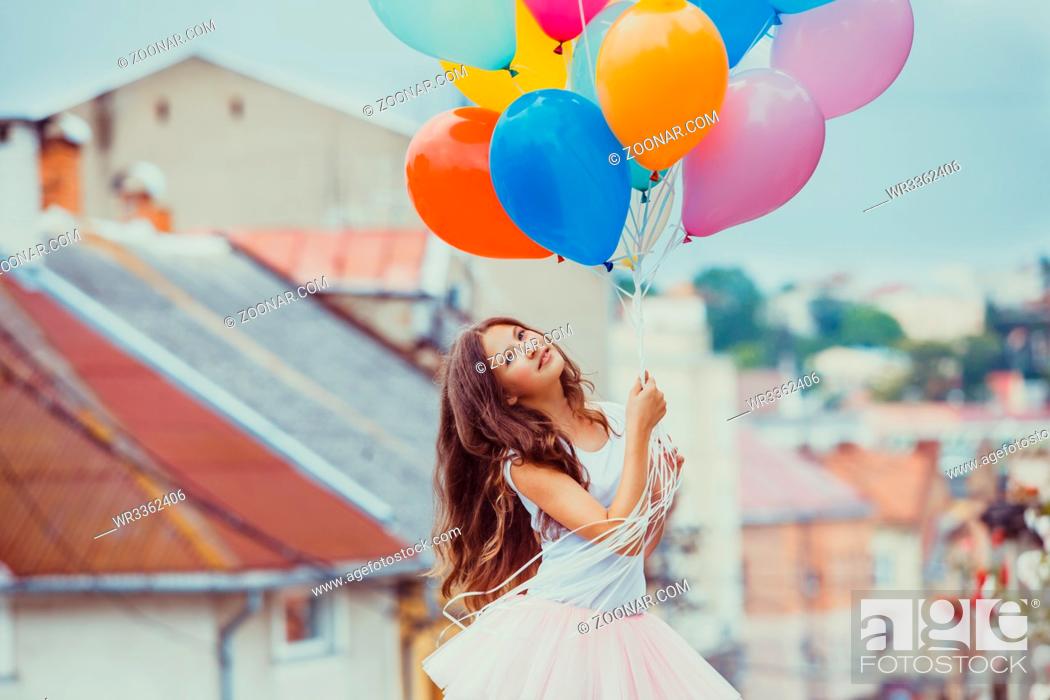 Stock Photo: Pretty girl with big colorful latex balloons posing in the street of an old town.