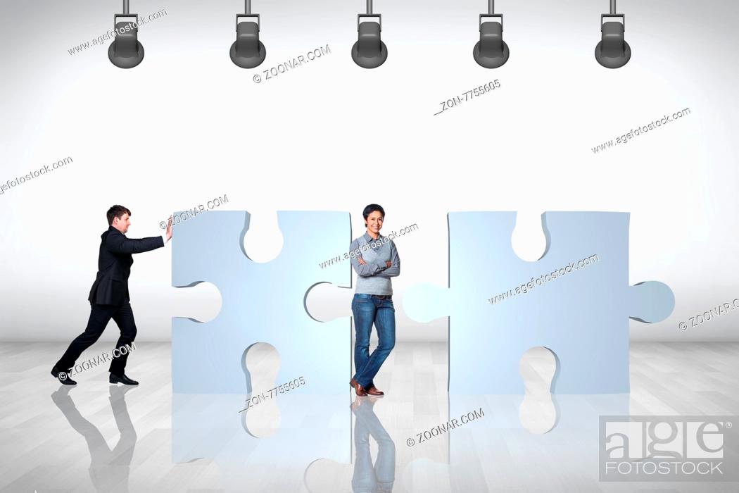 Stock Photo: Team of business people working together and try to join puzzle in the grey room.