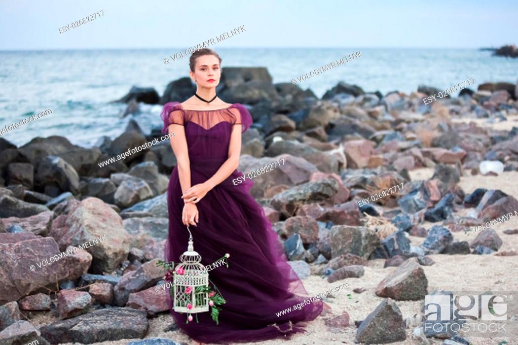 Imagen: The wedding day at the sea. Young romantic woman posing on the beach watching the sunset.